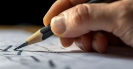 Hand writing marking on checklist box with pencil close up.